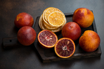 Black wooden serving tray with sicilian blood oranges and orange fruit chips, studio shot on a...