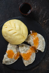 Above view of steamed korean pjan-se and potstickers on a stone slate tray, vertical shot, close-up