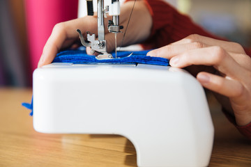 the master of sewing clothes works with the material, sewing on a typewriter in the workshop, preparing for the event, the hands of the master make even seams on the clothes,sewing machine