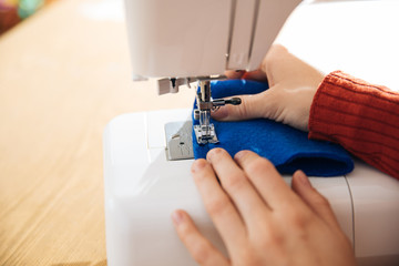 the master of sewing clothes works with the material, sewing on a typewriter in the workshop, preparing for the event, the hands of the master make even seams on the clothes,sewing machine