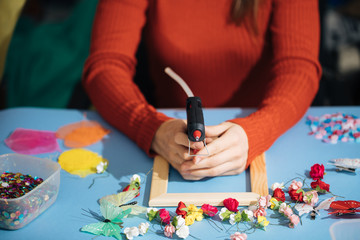 the master of decor decorates the photo frame with various colors and beauty objects, the decorator prepares equipment for the event top claas, the craftsman’s hands