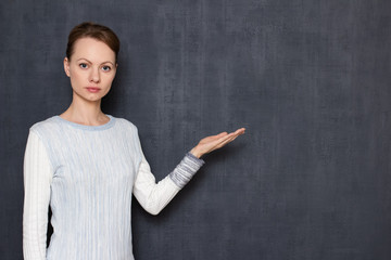 Portrait of serious focused girl pointing at copy space on right