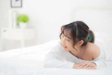 Obraz na płótnie Canvas Beautiful portrait young asian woman lying and smile while wake up with sunrise at morning, beauty cute girl happy and cheerful resting on bed in the bedroom, lifestyle and relax concept.