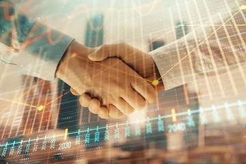 Plakat Double exposure of financial graph on cityscape background with two businessman handshake. Concept of stock market deal