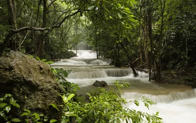 Abwaschbare Fototapete Olivgrün Wasserfall, der im Wald in den Fluss fließt