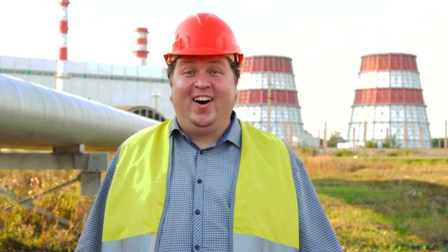 Surprised and shocked worker, engineer, or electrician looking at the camera standing in front of a power station