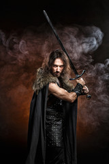 Man dressed in medieval armor and raincoat with longs word fighting against enemy. Courage fantasy...