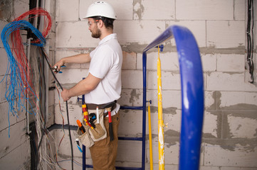 Electrician working near the Board with wires. Installation and connection of electrics.