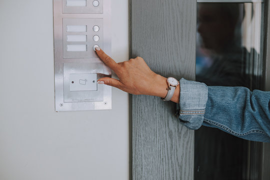 Hand of a Caucasian lady ringing the intercom