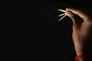 Hand holding an extinguished matchstick on black background. different extinguished matchstick