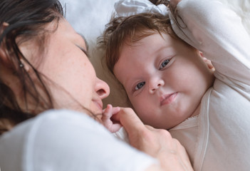 Mom lies with a newborn baby, top view.