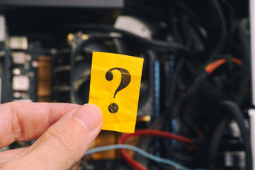 Hand holding question mark against open pc case