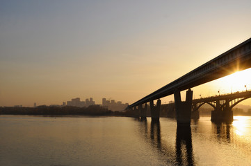 Fototapeta na wymiar Bridge over the river against the backdrop of the city sunset
