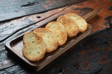 Toasted baguette slices isolated on rustic wooden kitchen table
