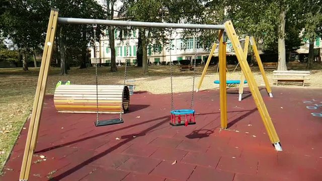 empty swings with chains swaying at playground for child, moved from wind,  slow motion