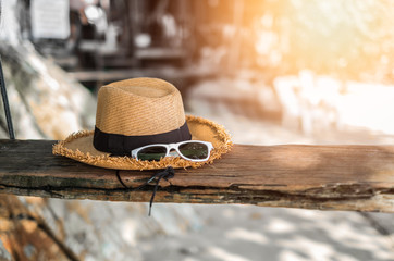 Hat and sunglasses or summer accessories on swing in sunlight at the beach. Vacation concept background