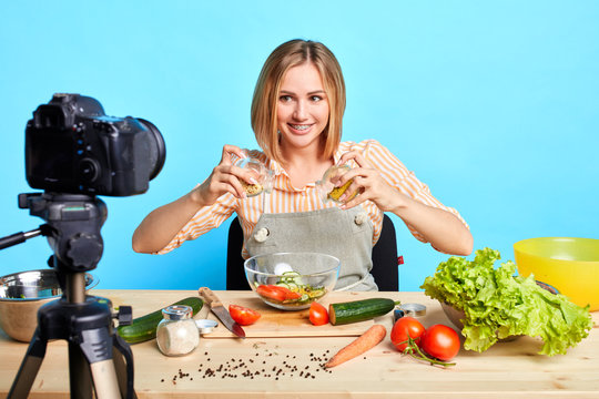 Popular dietitian blogger girl shooting cooking master class for her healthy food blog, making salad with pasta out of natural fresh products, using raw vegetables from local organic farm.