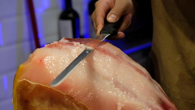 senior chef utting jamon prosciutto ham in a restaurant, italian or spanish cuisine