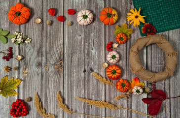 Composition for thanksgiving. Making decorations  on the door of handmade textile pumpkins and natural materials.  Wreath, autumn leaves, berries and cereals on a wooden background.