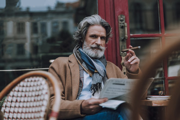 Frowning man with cigar and newspaper at the table stock photo