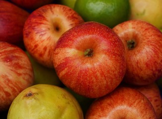 Close up of red apple with limes, guavas and apples in the background. Healthy food concept.