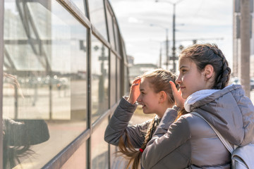 two girls girlfriends teenagers with smile straighten their hair and look in reflection of glass...