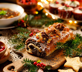 Christmas poppy seed cake covered with icing and decorated with raisins and walnuts on the holiday table. Traditional Christmas cake in Poland