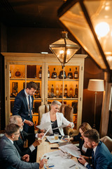 Brainstorming at business meeting, bbusineswoman sitting at conferebs table in white suit reading contract terms at bright office, sitting in soft chair, top view, background of different collectibles