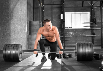 Fototapeta na wymiar Tired muscular man win a barbell in gym. Preparing to do deadlift exercise