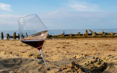 A glass of red wine on the sandy beach in summer.