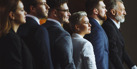 Noble attractive business people are taken a photo on dark background standing shoulder to...