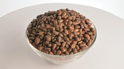 Pine nut rotate are on a table in a plate. Snack in transparent dish on an isolated white background are spinning moving.