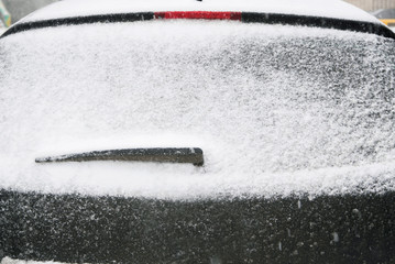 Close-up shot of a car's windscreen wiper covered in snow. snow on the car window. Snow-covered car windshield