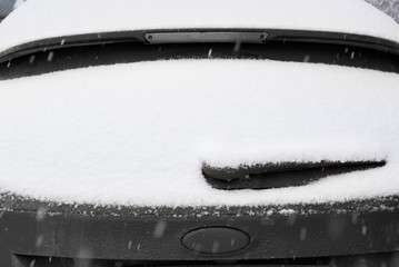 Close-up shot of a car's windscreen wiper covered in snow. snow on the car window. Snow-covered car...