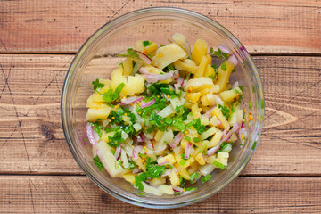 Step-by-step preparation of a German potato salad with sausage and cucumbers, step 2 adding boiled chopped potatoes, selective focus, top view