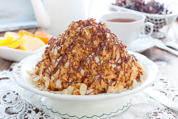 Traditional Russian anthill cake decorated with chocolate and almonds, horizontal