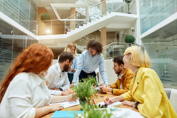 Young creative team of talented people solve work issues in modern office, work hard in good mood not looking at camera, horizontal shot