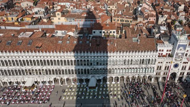 Aerial overhead time lapse of busy St Mark's Square with Campanile's shadow moving over Venice roofs, Italy
