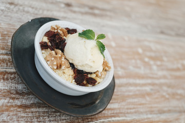 Apple crumble dessert with vanilla ice cream on the top on wooden table