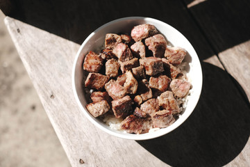 Homemade Bowl of Diced Beef Steak with rice Japanese style on wooden table.