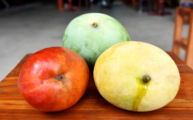 Yellow, green and red mango placed on the table on a blurred background