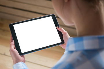 Over shoulder closeup view: woman hands holding digital tablet computer device with white blank screen in home interior. Mock up, copyspace, template, entertainment and technology concept