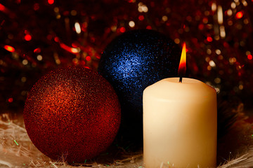 On a multicolored background candle and Christmas balls.