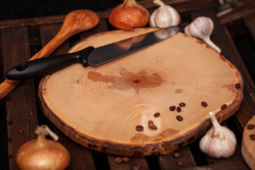 wood crafted cutting board with knife onions garlic and coffee beans