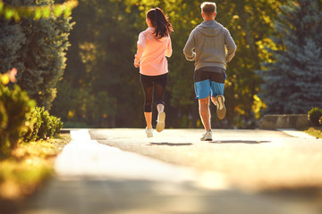 Sporty couple are running along the city street in the morning.