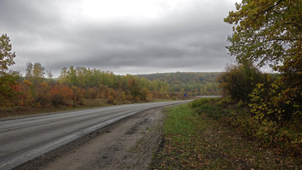Autumn road on a cloudy foggy morning