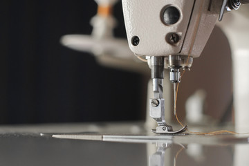 Close-up needle of white industrial sewing machine use sew cloth.