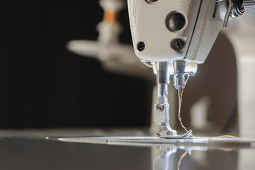 Close-up needle of white industrial sewing machine use sew cloth.