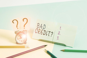 Writing note showing Bad Creditquestion. Business concept for inabilityof a demonstrating to repay a debt on time and in full Mini size alarm clock beside stationary on pastel backdrop