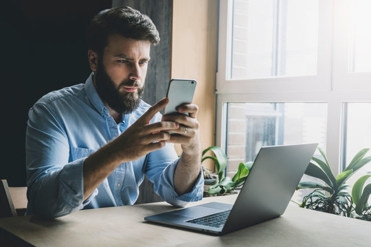 Office worker relaxing, playing online games on smartphone. Man downloading interesting apps on his mobile device. Home-based freelancer looking for instructions on its work. Male adult checking email